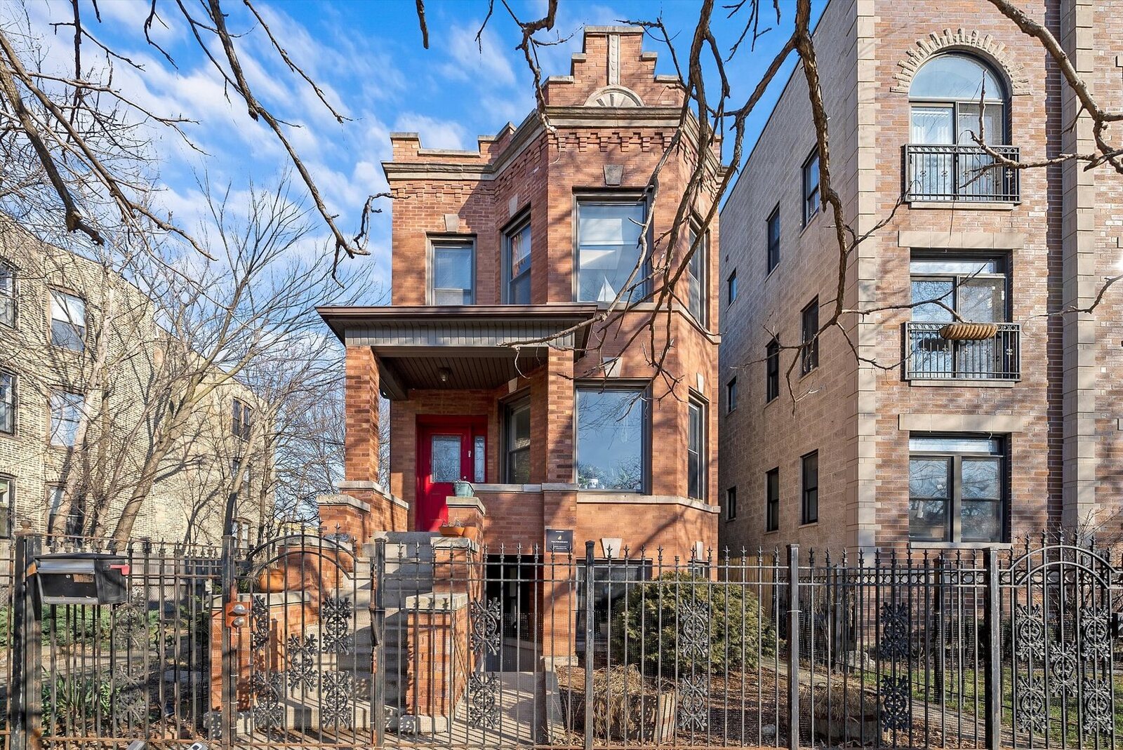 A classic Chicago brick two-flat: stepped parapet with sunburst brickwork, front porch, stacked bay