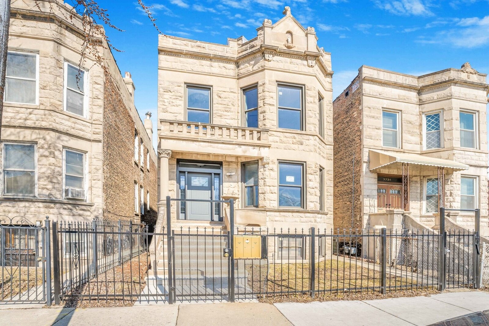A Chicago greystone two-flat: rough-cut limestone front, stacked bay windows, carved pediment parapet